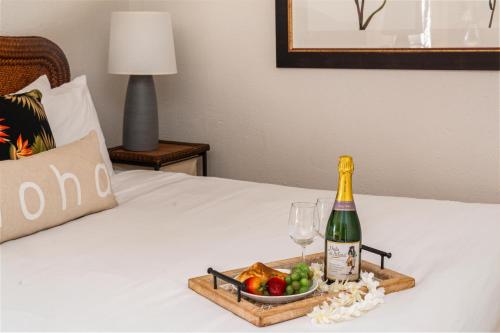 a tray with a bottle of champagne and a bowl of fruit at Paki Maui 217 · PM 217 Cozy 1BR Oceanfront Condo w Pool in Lahaina