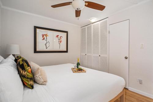 a bedroom with a white bed and a ceiling fan at Paki Maui 217 · PM 217 Cozy 1BR Oceanfront Condo w Pool in Lahaina
