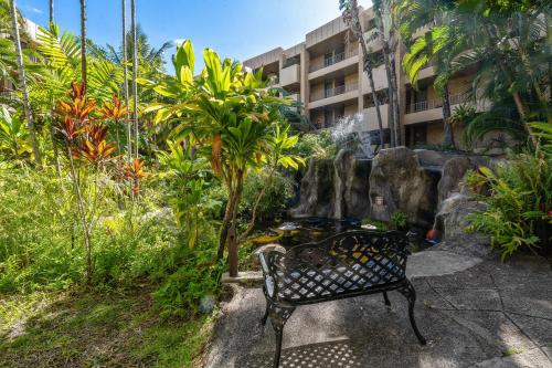 a bench sitting in front of a fountain in a garden at Paki Maui 217 · PM 217 Cozy 1BR Oceanfront Condo w Pool in Lahaina