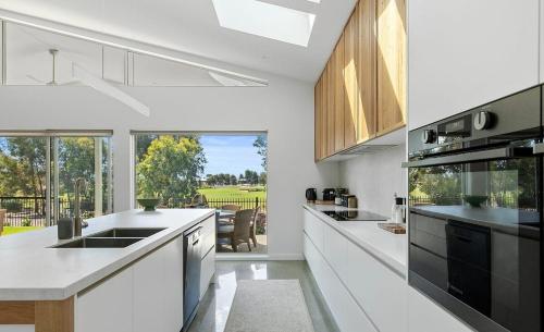 a kitchen with white counters and a large window at Paradise on the Fairway in Yarrawonga