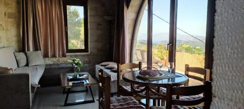 a living room with a table and chairs and a large window at Vasiliki's Residence Amazing View in Kissamos