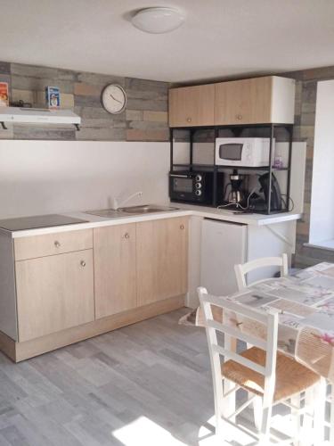 une cuisine avec un comptoir, une table et un four micro-ondes dans l'établissement Appartement moderne à Cornimont 30 m² avec vue montagne, à Cornimont