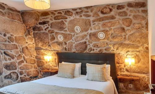 ein Schlafzimmer mit einer Steinmauer und einem Bett in der Unterkunft Comfortable house in Lindoso, stunning mountain view in Pedras de Moledo