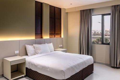 a bedroom with a large bed and a window at Jarzez Hotel Apartments Al Hail in Seeb