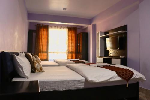 a bedroom with three beds with a window at Darjeeling Homes The Grace in Darjeeling