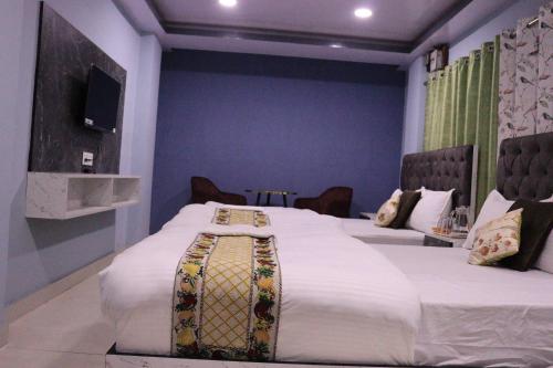 a bedroom with two beds and a tv on the wall at Darjeeling Homes The Grace in Darjeeling