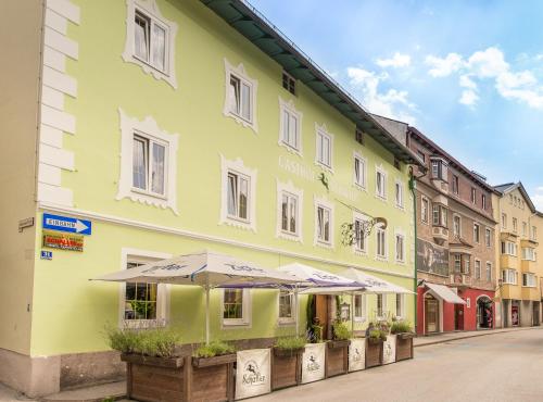 a green building with umbrellas on a street at Gasthof Einhorn Schaller in Schwaz