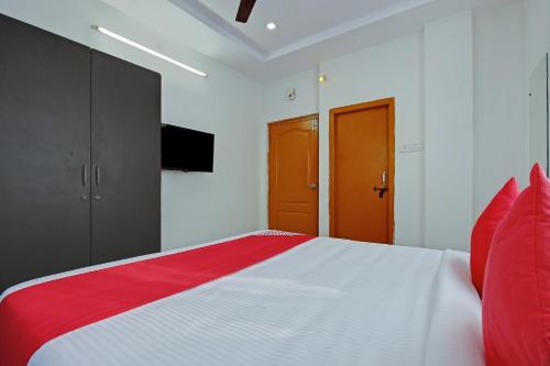 a bedroom with a red and white bed and a television at Super Hotel O Golden Hive Madhapur Near Shilparamam in Hyderabad