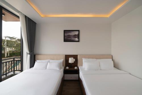 two beds in a room with a balcony at Anteaus Hotel Đà Lạt in Da Thien