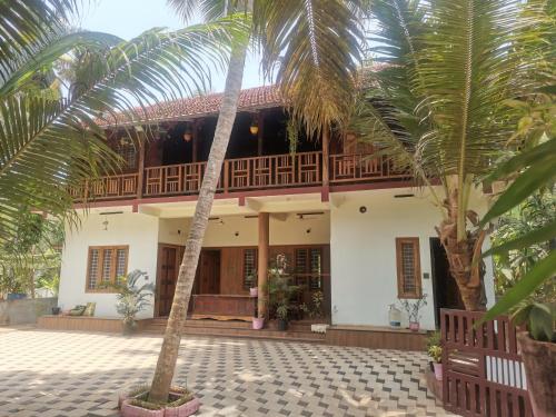 a house with palm trees in front of it at Kailasahomestay & Ayurvedic Spa in Pūvār