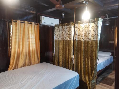 a couple of beds in a room with curtains at Kailasahomestay & Ayurvedic Spa in Pūvār
