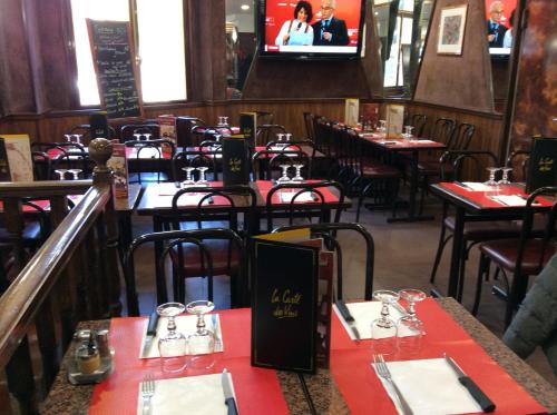 une salle à manger avec des tables, des chaises et une télévision dans l'établissement Hotel De La Place, à Malakoff