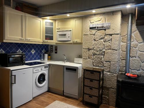 eine Küche mit weißen Geräten und einer Steinmauer in der Unterkunft Apartamento Selva Blanca 9 in Villanúa