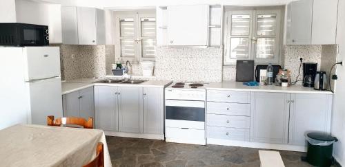 a kitchen with white cabinets and white appliances at House with sea view in Porto Heli, fireplace and garden in Porto Heli