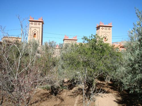a building with two towers behind some trees at Kasbah Ait Kassi in Boumalne