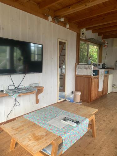 a living room with a table and a tv on the wall at HealingDragon Ryugu cottage in Shimoda