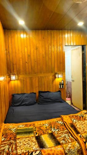 a bed in a room with a wooden wall at Altaf's motel in Matheran