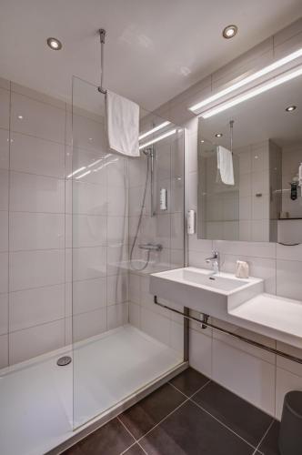 a white bathroom with a sink and a shower at Mezzo Hotel & Business in Beringen