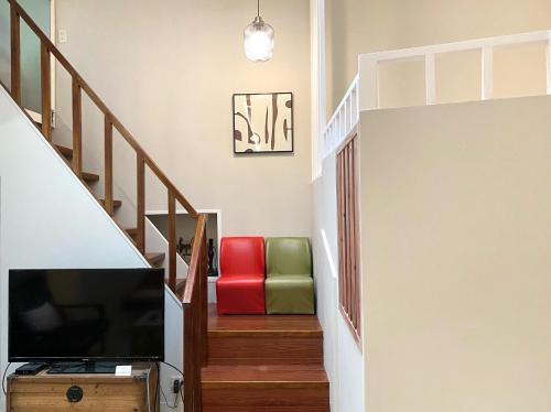 un soggiorno con TV e sedia rossa e verde di 寵物友善九份沐石原宿一館mu shi b&b a Ruifang