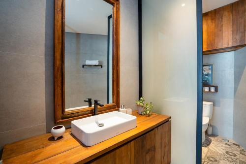 a bathroom with a white sink and a mirror at Villa Casa Goya - Lofty Pool Villa Near The Beach in Vibrant Legian in Legian
