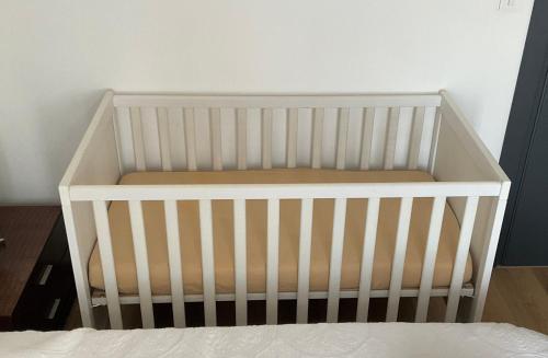 a white crib in a room with a bed at Villa Perla del Sole in Baiardo