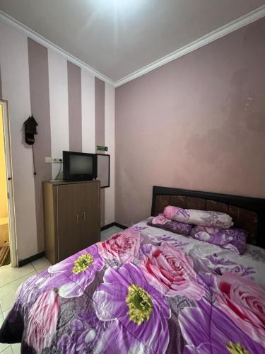a bedroom with a bed with flowers on it at Ken's Villa 8 in Batu