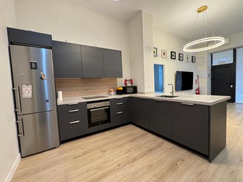 a kitchen with black cabinets and a stainless steel refrigerator at LUXURY SUITE Wifi AC SERVICIOS EN LA PUERTA in Madrid