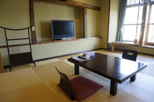 a living room with a table and a tv at ワインとお宿千歳Chitose in Monju