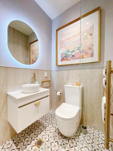 a bathroom with a toilet and a sink and a mirror at Studio 524- Stylish Urban Retreat on Central Queen Street in Auckland