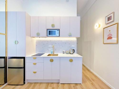 a white kitchen with a sink and a microwave at Studio 524- Stylish Urban Retreat on Central Queen Street in Auckland