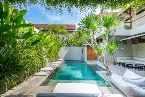 a pool in the backyard of a house with palm trees at Vassani Stay in Canggu