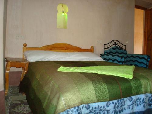 a bedroom with a bed with a green blanket on it at Kasbah Ait Kassi in Boumalne