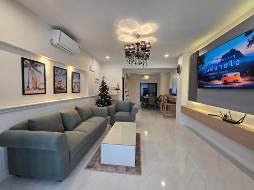 a living room with a couch and a tv at The Bliss House Bangsaen in Ban Laem Thaen