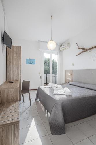 a bedroom with a bed and a desk and a television at Hotel Astrid in Cervia