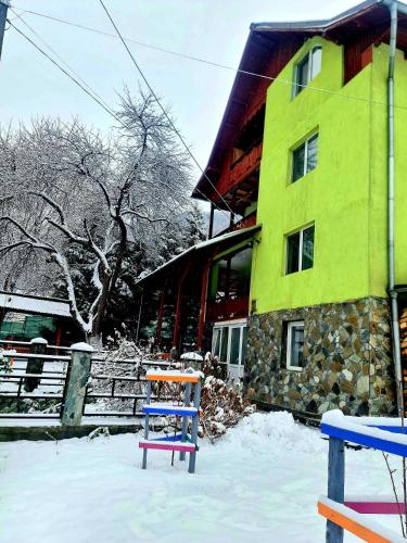 a brightly colored building with a bench in the snow at Vila Giulia Voineasa in Voineasa