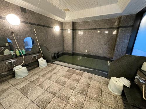 a bathroom with a bath tub with two toilets at Hotel Route-Inn Asahikawa Ekimae Ichijodori in Asahikawa