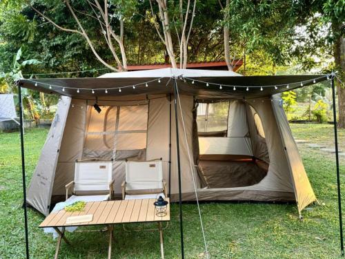 a tent with two chairs and a table in the grass at Rim Haad Villa and Camping Space in Ban Tanjong In