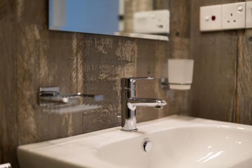 a bathroom sink with a faucet and a mirror at Greenwood Edge Kandy in Kandy