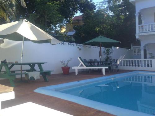 a swimming pool with a picnic table and an umbrella at Almond tree villa in Ocho Rios