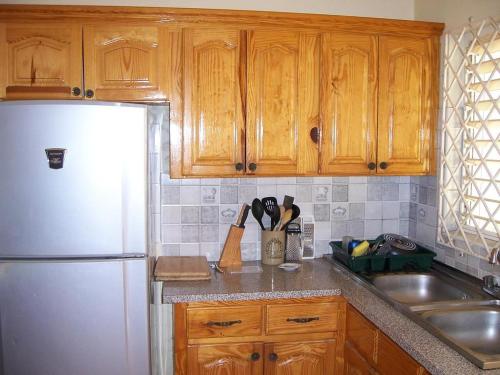 a kitchen with wooden cabinets and a white refrigerator at Almond tree villa in Ocho Rios