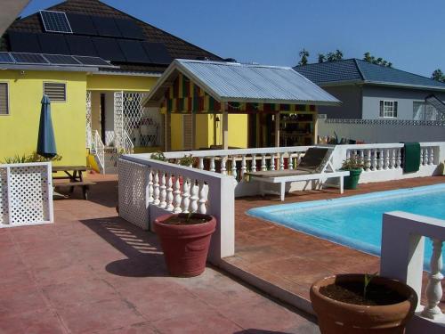 a house with a swimming pool and a yellow house at Almond tree villa in Ocho Rios