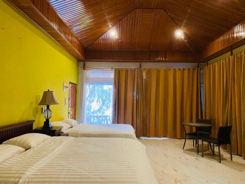 a bedroom with three beds and a desk and a window at Sunmoon Beach Resort Likupang Timur in Pulau Mogogimbun