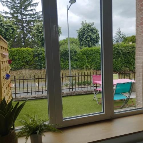 - une fenêtre donnant sur une terrasse avec une table et des chaises dans l'établissement Chez Coralie et Jean, à Saint-Pierre-Montlimart