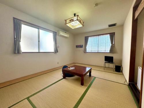 a living room with a table and two windows at ビジネスホテル美咲 in Sakaide