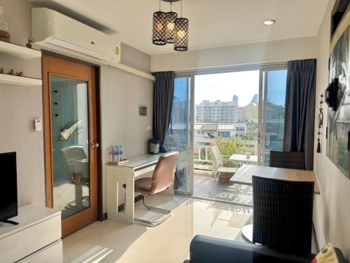a living room with a desk and a balcony at Baan Sabai Rama IV Apartment in Bangkok