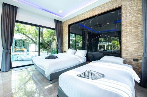 2 łóżka w pokoju z dużymi oknami w obiekcie Crystal Cove Pool Villa Pattaya w mieście Ban Huai Yai