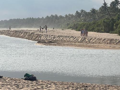a group of people standing on the beach near the water at Seth Villa by Magampura Resorts in Tangalle