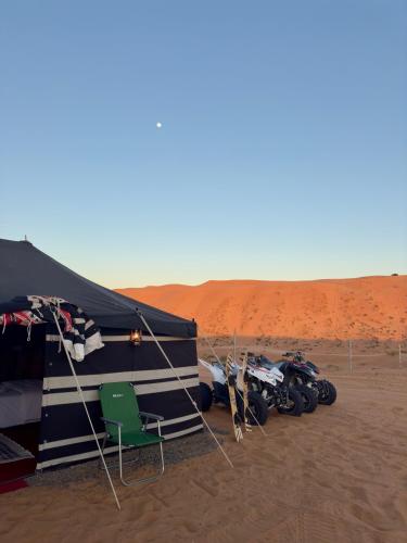 a group of motorcycles parked next to a tent in the desert at Desert Hills Oman Bidiyah Camp in Bidiyah