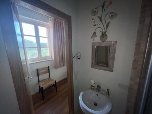 baño con lavabo, espejo y silla en Maremma Toscana a Scarlino elegante appartamento, en Scarlino
