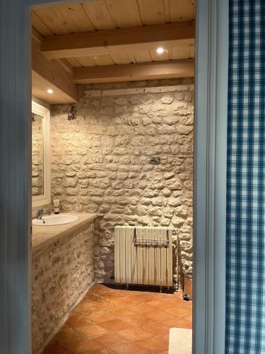 une salle de bains en pierre avec lavabo et radiateur dans l'établissement La Charentaise Dorée, à Juillac-le-Coq